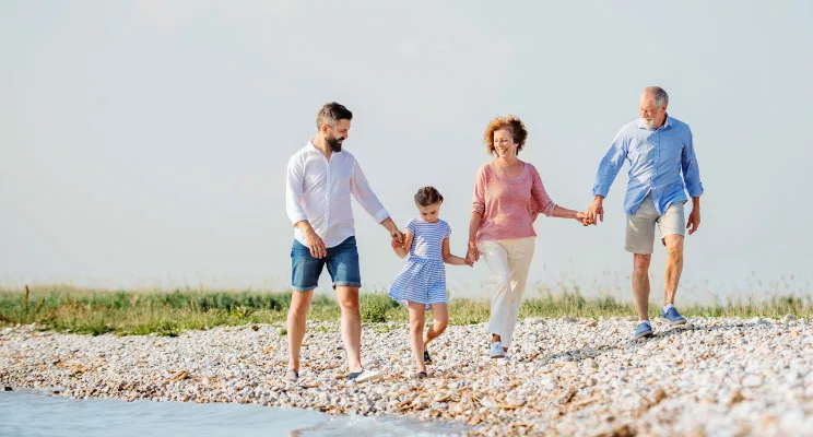 Three generations holding hands on a pebble beach