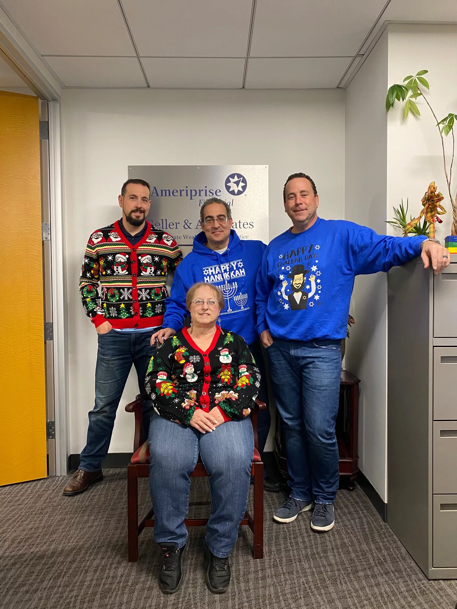 Four team members in holiday sweaters in the Ameriprise office