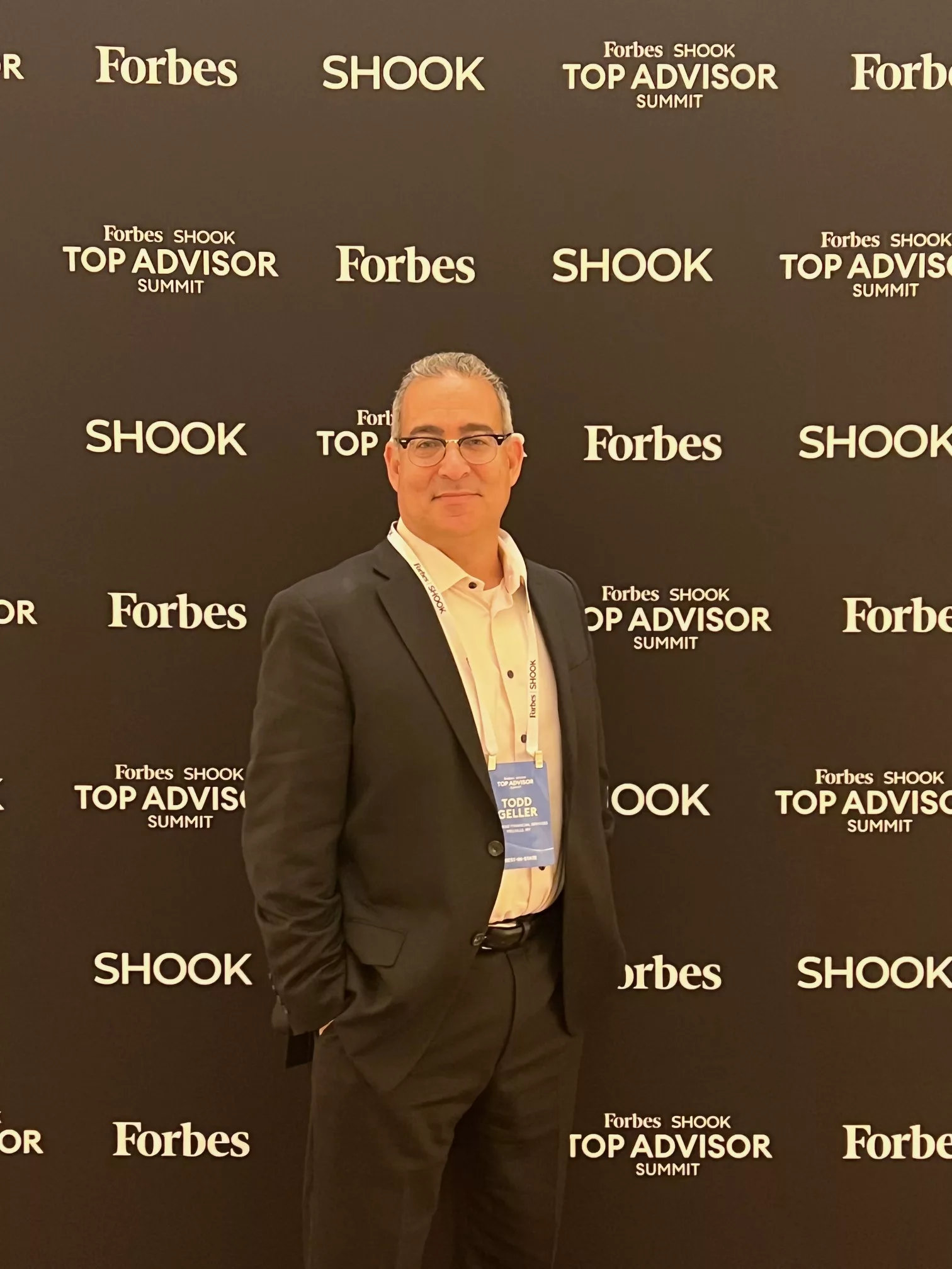 Advisor in a blazer in front of a Forbes SHOOK Top Advisor Summit backdrop