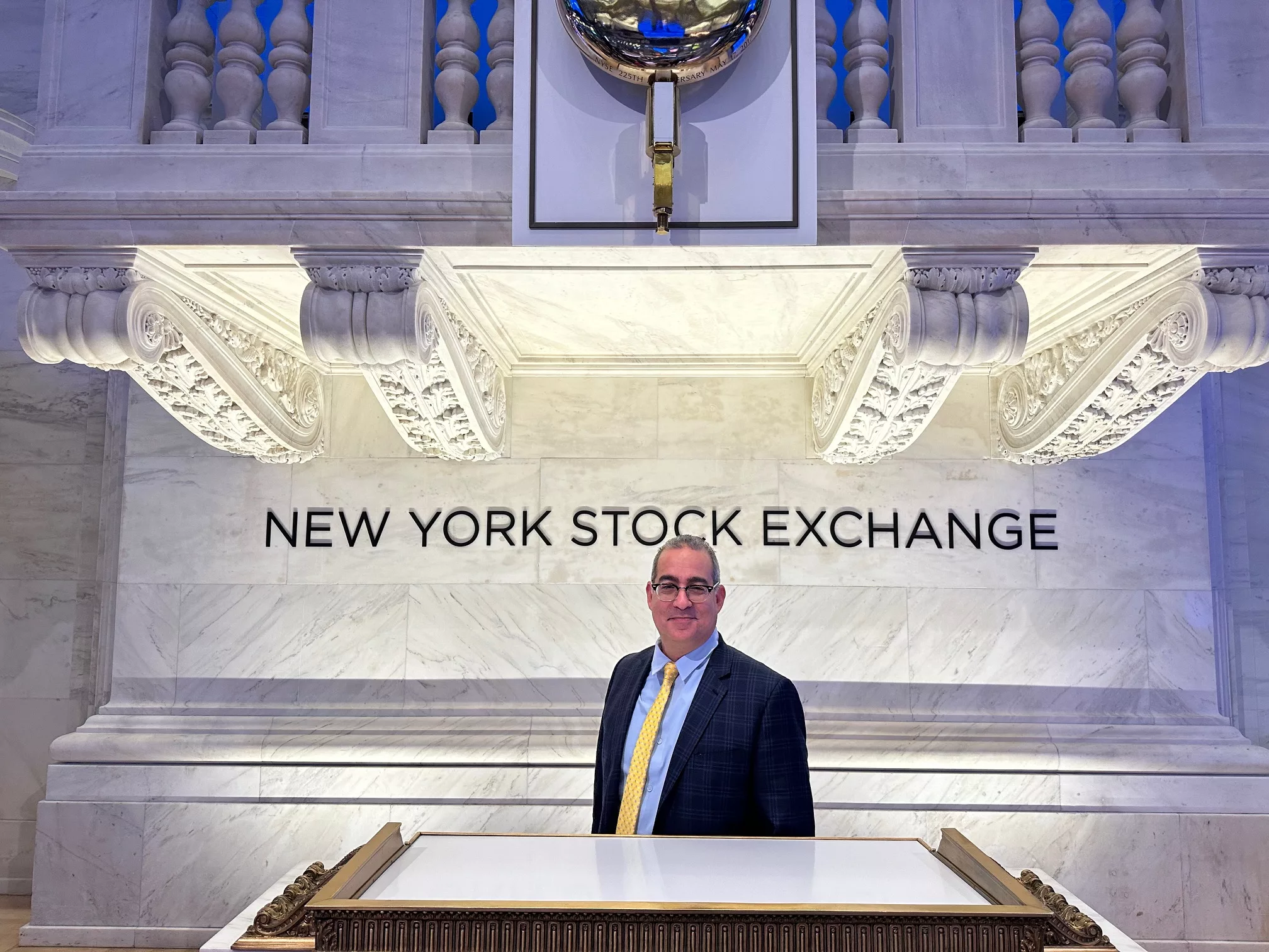 Advisor in a suit standing at the podium under the New York Stock Exchange sign