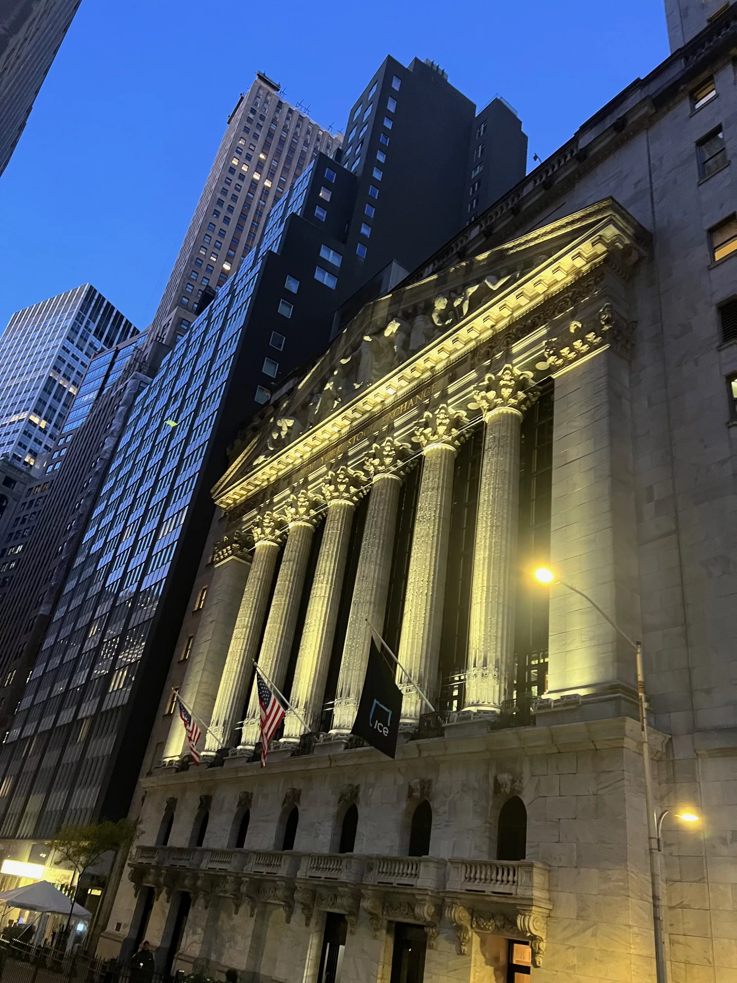 Facade of the New York Stock Exchange on Wall Street lit up at dusk