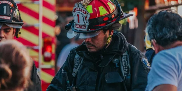 Firefighters in turnout gear and helmets at the scene beside a fire truck