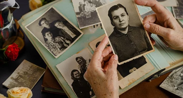 Hands holding an old black-and-white family photo over a photo album