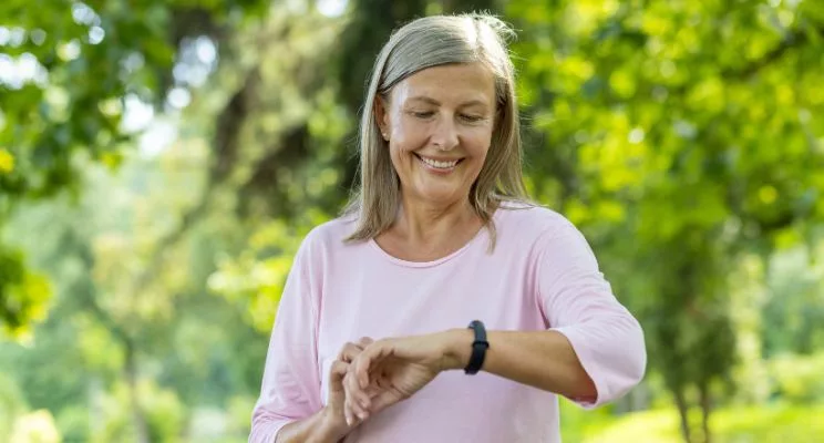 Smiling older woman checking her smartwatch outdoors