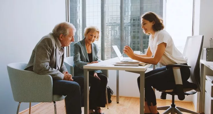 Older couple meeting with an advisor at a desk by an office window